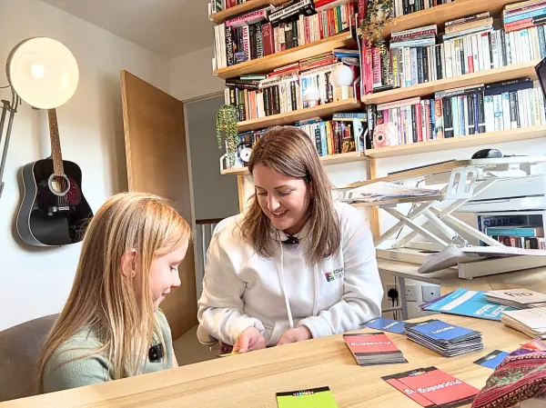 An Educamus tutor working through number cards with a primary age pupil at home